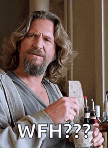 a man with long hair and a beard is holding a bottle of whiskey and says " wfh "