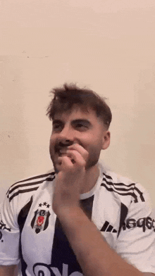 a man with a beard is wearing a white and black striped shirt and eating something .
