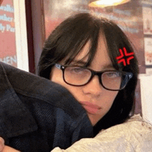 a woman wearing glasses and a red sticker on her head is hugging a man .