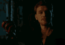 a man is holding a bloody hand in his mouth in a dark room