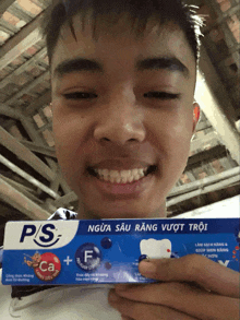 a boy is holding a toothpaste that says ps on it