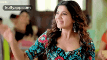 a woman in a blue and black floral dress is smiling and dancing .