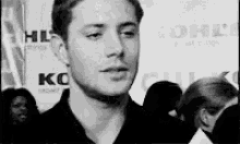 a man in a black shirt is talking to a group of people .