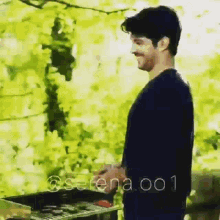 a man in a black shirt is standing in front of a grill with the words serena.001 on the bottom