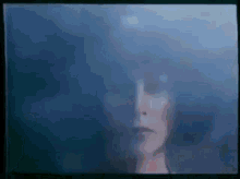 a blurred image of a woman 's face with a blue background