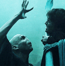 a man and a woman are standing next to each other and the man is reaching up towards the woman