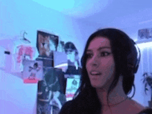 a woman wearing headphones is standing in a room with a lot of pictures on the wall .