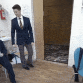 a man in a suit and tie is standing in front of a door