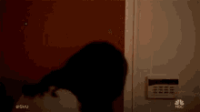a man with blood on his face is standing in a doorway with a nbc remote control in the background