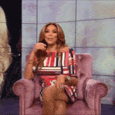 a woman is sitting in a pink chair with her legs crossed