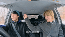 two men are sitting in a car and one of them is wearing a hat