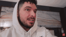a man with a beard is wearing a white hoodie with the word tommy on it
