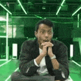 a man in a suit and tie is sitting in a green room .