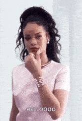 a woman in a pink shirt is holding her finger to her mouth and talking .