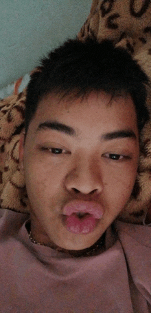 a young man laying on a bed with his mouth open and his tongue sticking out