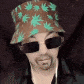 a man wearing a hat and sunglasses is smiling .
