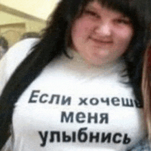 a woman wearing a white t-shirt with russian writing on it is smiling .