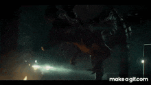 a t-rex is walking down a street at night .