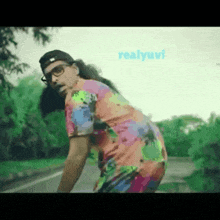 a man in a colorful shirt is standing on the side of a road with the words realyuvi behind him