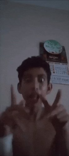 a man without a shirt is making a funny face in front of a wall calendar