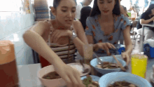 two women are sitting at a table eating food