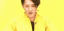 a young man wearing a yellow jacket is making a funny face