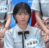 a girl wearing a blue shirt and a black bow tie has a name tag that says ' ao ' on it