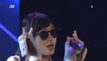 a woman singing into a microphone with the word live on the bottom right