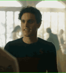 a young man with curly hair wearing a black shirt smiles