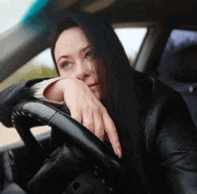 a woman leaning on the steering wheel of a car