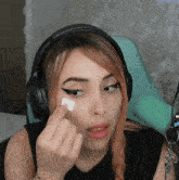 a woman wearing headphones has a piece of paper on her eye
