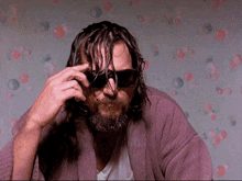a man with a beard wears sunglasses and a robe
