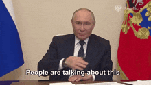 a man in a suit and tie says people are talking about this in front of flags