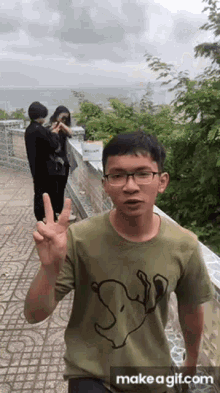 a man wearing a green shirt with snoopy on it giving the peace sign
