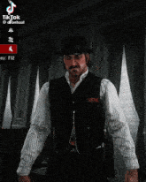 a man in a cowboy hat and vest is standing in front of a window with tiktok written on the bottom right corner