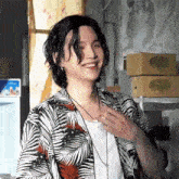 a man with long hair is wearing a hawaiian shirt and a necklace and smiling .