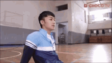 a young man is sitting on the floor of a gym .