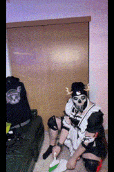 a man in a maid costume is sitting on the floor holding a broom