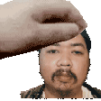a hand is touching a man 's forehead with a beard .