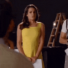 a woman in a yellow dress is standing in front of a man in a suit .