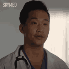 a man in a white lab coat with a stethoscope around his neck and the word skymed behind him