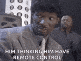 a man in a suit and tie is talking to another man while holding a remote control .