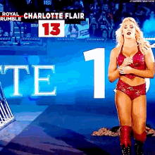 a woman in a red outfit is standing in front of a sign that says royal rumble charlotte flair