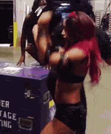 a woman with red hair is standing in front of a purple box that says ' cage ' on it .
