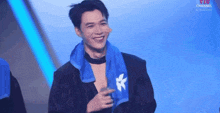 a man wearing a blue towel around his neck is smiling on a stage .
