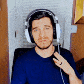 a man wearing a blue shirt and white headphones is making a funny face