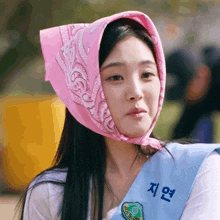 a woman wearing a pink bandana on her head and a blue sash that says " 지연 "