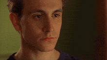 a close up of a young man 's face with a striped shirt on