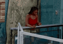 a woman in a red tank top is sitting on a balcony .