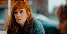 a woman with red hair is looking at another woman
